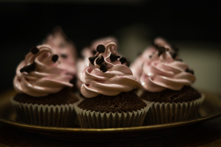 Chocolate muffins with pink whipped cream and cocoa nibsの写真素材