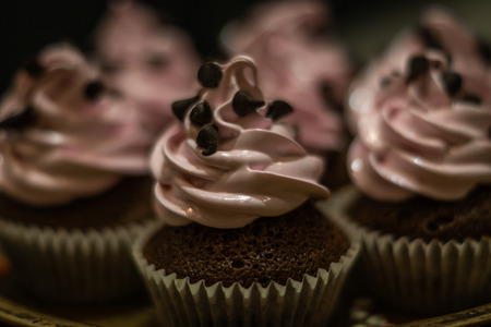 Chocolate muffins with pink whipped cream and cocoa nibsの写真素材