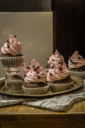 Chocolate muffins with pink whipped cream and cocoa nibsの写真素材