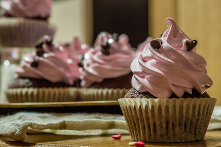 Chocolate muffins with pink whipped cream and cocoa nibsの写真素材