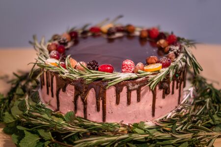 Wild berry Birthday cake with chocolate glaze, rosemary and berries on topの写真素材