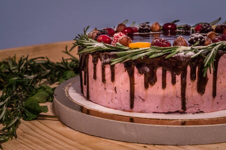 Wild berry Birthday cake with chocolate glaze, rosemary and berries on topの写真素材