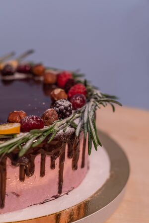 Wild berry Birthday cake with chocolate glaze, rosemary and berries on topの写真素材