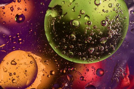Unusual colorful background with oil drop circles and air bubbles that reflect yellow, orange, purple, green and red colors. Color spots intentionally unfocused. Cosmic space and galaxy concept.の写真素材