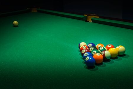 Set of used colorful numbered balls on old green billiards table. Horizontal background with...