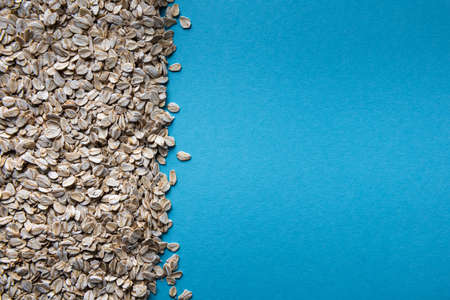 Background with natural dry rolled oats and with large square copy space on blue paper texture....