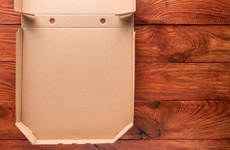 Natural redwood background with part of new clean brown opened empty pizza box made of paperboard....