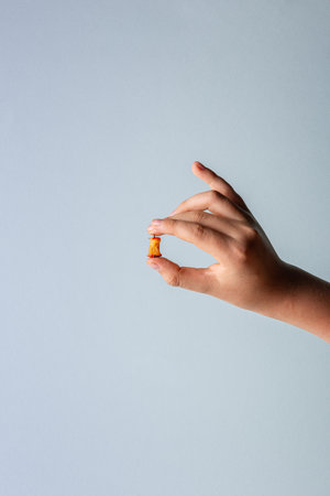 Hand of Caucasian teenager boy with haw stump in fingers. Small raw fruit leftovers in human hand. Copy space. Unrecognizable person. Vertical orientation. Healthy eating concept. Blue background.の写真素材