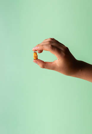 Hand of Caucasian boy with little haw stump in fingers. Fruit leftovers in teenager hand. Copy space. Unrecognizable person. Vertical orientation. Healthy eating concept. Green mint background.の写真素材