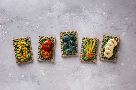 Homemade sandwiches with tomato, banana, blueberry, corn, pepper, chlorella, spirulina and cheese on...