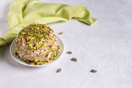 Sesame halva with pistachios on top, few scattered nuts, green linen napkin and copy space. Turkish delight. Traditional middle eastern sweets. Jewish, turkish, arabic dessert. White background.の写真素材