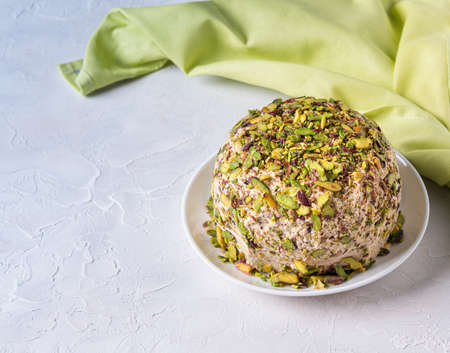 Sesame halva with pistachios nuts on white background with green linen napkin on side and copy space. Turkish delight. Traditional middle eastern sweets. Jewish, turkish, arabic national dessert.の写真素材