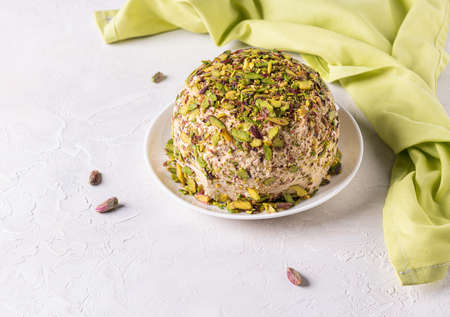Ready to eat halva with pistachios on top, few scattered nuts, green linen napkin on side. Turkish delight. Traditional middle eastern sweets. Jewish, turkish, arabic dessert. Horizontal orientationの写真素材