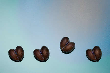 Imperfect row of four ripe brown and blue natural heart shaped plums on multicolored peach, blue and green textured paper background. Pattern with hard shadows. Copy space. View from directly above.の写真素材