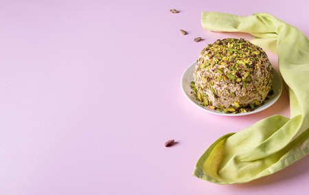 Halva with pistachios, scatterred nuts and green linen napkin on pink paper. Horizontal orientation. Large copy space. Traditional middle eastern sweets. Jewish, turkish, arabic national dessert.の写真素材