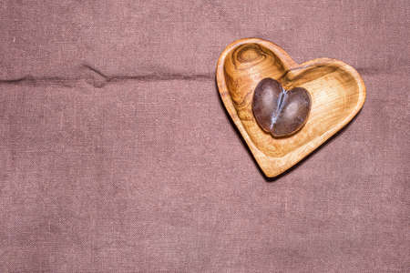 Ripe brown and blue natural malformed imperfect plum with crack in middle on wooden heart shaped...
