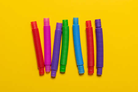 Row of few new straight colorful red, blue, pink, green and yellow pop tube children toys. Set of...