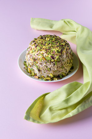 Sesame halva with pistachios on white plate on pink background with green linen napkin. High angle view. Traditional middle eastern sweets. Jewish, turkish, arabic national dessert. Turkish delight.の写真素材