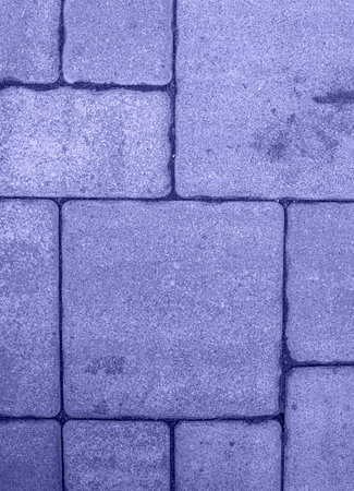Close up of straight street pavement surface. Geometric pattern of square blocks of different size. Textured rough background toned in very peri, color of year 2022. Directly above view. Copy spaceの写真素材