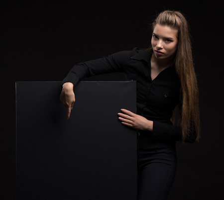 Young happy woman showing presentation, pointing on placard overの写真素材