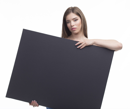 Young sexy woman portrait of a confident businesswoman showing presentation, pointing paper placard black background. Ideal for banners, registration forms, presentation, landings, presenting concept.の写真素材