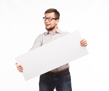 Young happy man portrait of a confident businessman showing presentation, pointing paper placard gray background. Ideal for banners, registration forms, presentation, landings, presenting concept.の写真素材