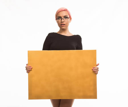 Young surprised woman portrait of a confident businesswoman showing presentation, pointing placard gray background. Ideal for banners, registration forms, presentation, landings, presenting concept.の写真素材
