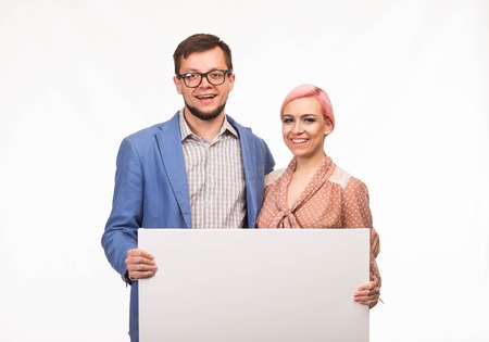 Young happy couple portrait of a confident businessman showing presentation, pointing paper placard background. Ideal for banners, registration forms, presentation, landings, presenting concept.の写真素材