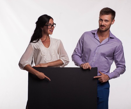 Young confident woman portrait of a confident businesswoman showing presentation, pointing placard gray background. Ideal for banners, registration forms, presentation, landings, presenting concept.の写真素材