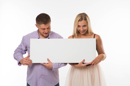 Young surprised couple portrait of a confident businessman showing presentation, pointing placard gray background. Ideal for banners, registration forms, presentation, landings, presenting concept.の写真素材