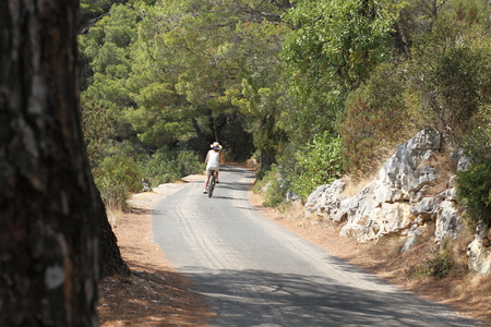 Woman biker on winding road through the woods.の写真素材