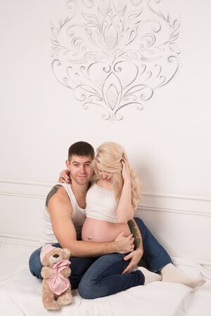 Beautiful pregnant couple in love on the background. Hands of husband on the tummy of his pregnant wife. Young man tenderly stroked pregnant belly of his wife. Husband kissing pregnant belly.の写真素材