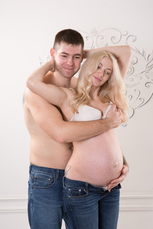 Beautiful pregnant couple in love on the background. Hands of husband on the tummy of his pregnant wife. Young man tenderly stroked pregnant belly of his wife. Husband kissing pregnant belly.の写真素材