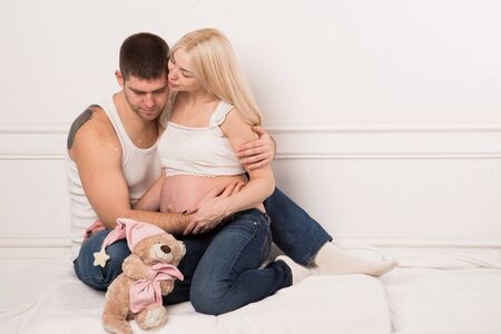 Beautiful pregnant couple in love on the background. Hands of husband on the tummy of his pregnant wife. Young man tenderly stroked pregnant belly of his wife. Husband kissing pregnant belly.の写真素材