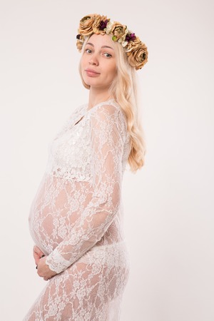 Happy pregnant young woman in love on the background. Hands on the tummy. Young mom tenderly stroked pregnant belly with unborn baby.の写真素材
