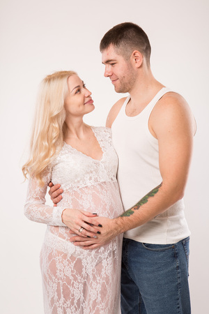 Beautiful pregnant couple in love on the background. Hands of husband on the tummy of his pregnant wife. Young man tenderly stroked pregnant belly of his wife. Husband kissing pregnant belly.の写真素材