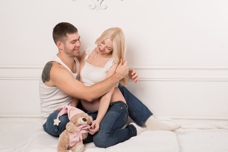 Beautiful pregnant couple in love on the background. Hands of husband on the tummy of his pregnant wife. Young man tenderly stroked pregnant belly of his wife. Husband kissing pregnant belly.の写真素材
