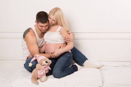 Beautiful pregnant couple in love on the background. Hands of husband on the tummy of his pregnant wife. Young man tenderly stroked pregnant belly of his wife. Husband kissing pregnant belly.の写真素材