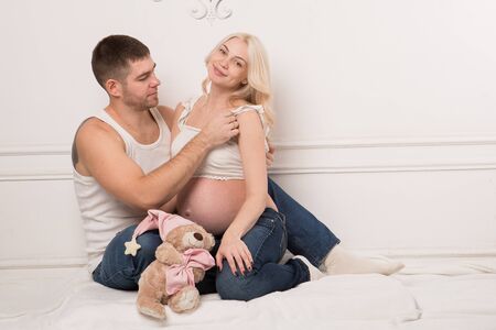 Beautiful pregnant couple in love on the background. Hands of husband on the tummy of his pregnant wife. Young man tenderly stroked pregnant belly of his wife. Husband kissing pregnant belly.の写真素材