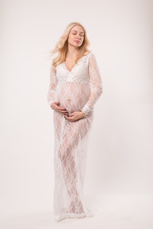 Happy pregnant young woman in love on the background. Hands on the tummy. Young mom tenderly stroked pregnant belly with unborn baby.の写真素材