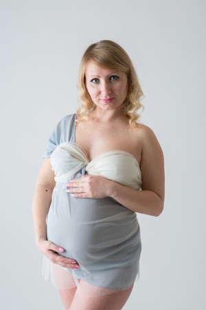 Happy pregnant young woman in love on the background. Hands on the tummy. Young mom tenderly stroked pregnant belly with unborn baby.の写真素材