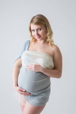 Happy pregnant young woman in love on the background. Hands on the tummy. Young mom tenderly stroked pregnant belly with unborn baby.の写真素材