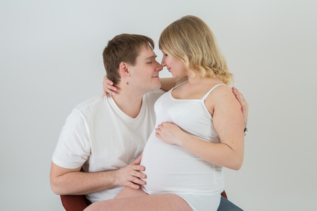 Beautiful pregnant couple in love on the background.Hands of husband on the tummy of his pregnant wife. Young man tenderly stroked pregnant belly of his wife. Husband kissing pregnant belly.の写真素材