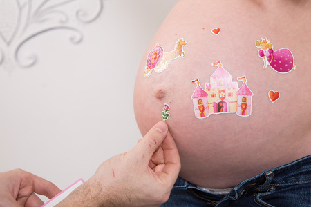Beautiful pregnant couple in love on the background. Hands of husband on the tummy of his pregnant wife. Young man tenderly stroked pregnant belly of his wife. Husband kissing pregnant belly.の写真素材
