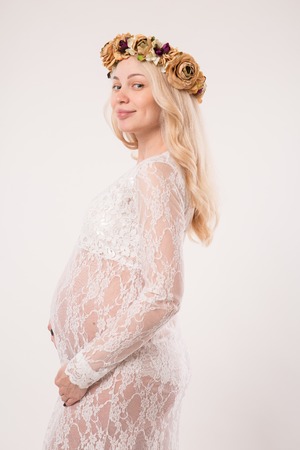 Happy pregnant young woman in love on the background. Hands on the tummy. Young mom tenderly stroked pregnant belly with unborn baby.の写真素材