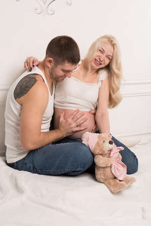 Beautiful pregnant couple in love on the background. Hands of husband on the tummy of his pregnant wife. Young man tenderly stroked pregnant belly of his wife. Husband kissing pregnant belly.の写真素材