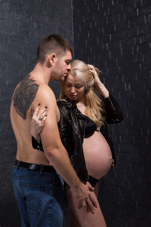 Beautiful pregnant couple in love on the background. Hands of husband on the tummy of his pregnant wife. Young man tenderly stroked pregnant belly of his wife. Husband kissing pregnant belly.の写真素材