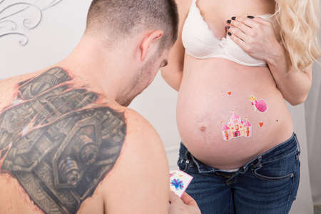 Beautiful pregnant couple in love on the background. Hands of husband on the tummy of his pregnant wife. Young man tenderly stroked pregnant belly of his wife. Husband kissing pregnant belly.の写真素材