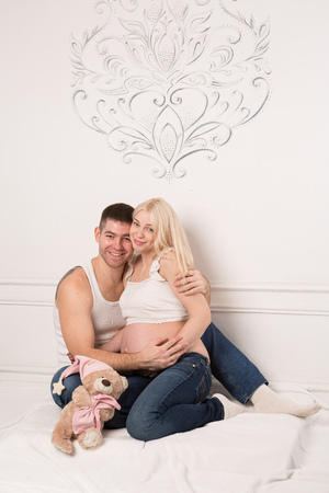 Beautiful pregnant couple in love on the background. Hands of husband on the tummy of his pregnant wife. Young man tenderly stroked pregnant belly of his wife. Husband kissing pregnant belly.の写真素材