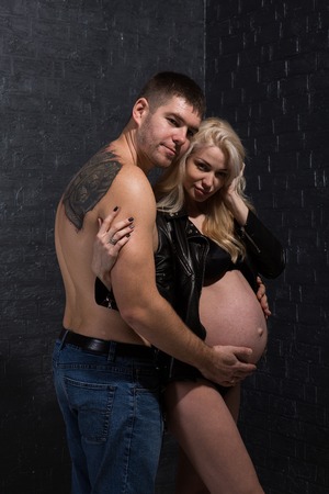 Beautiful pregnant couple in love on the background. Hands of husband on the tummy of his pregnant wife. Young man tenderly stroked pregnant belly of his wife. Husband kissing pregnant belly.の写真素材